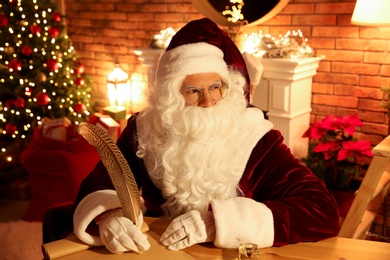 Santa Claus writing letter at table indoors