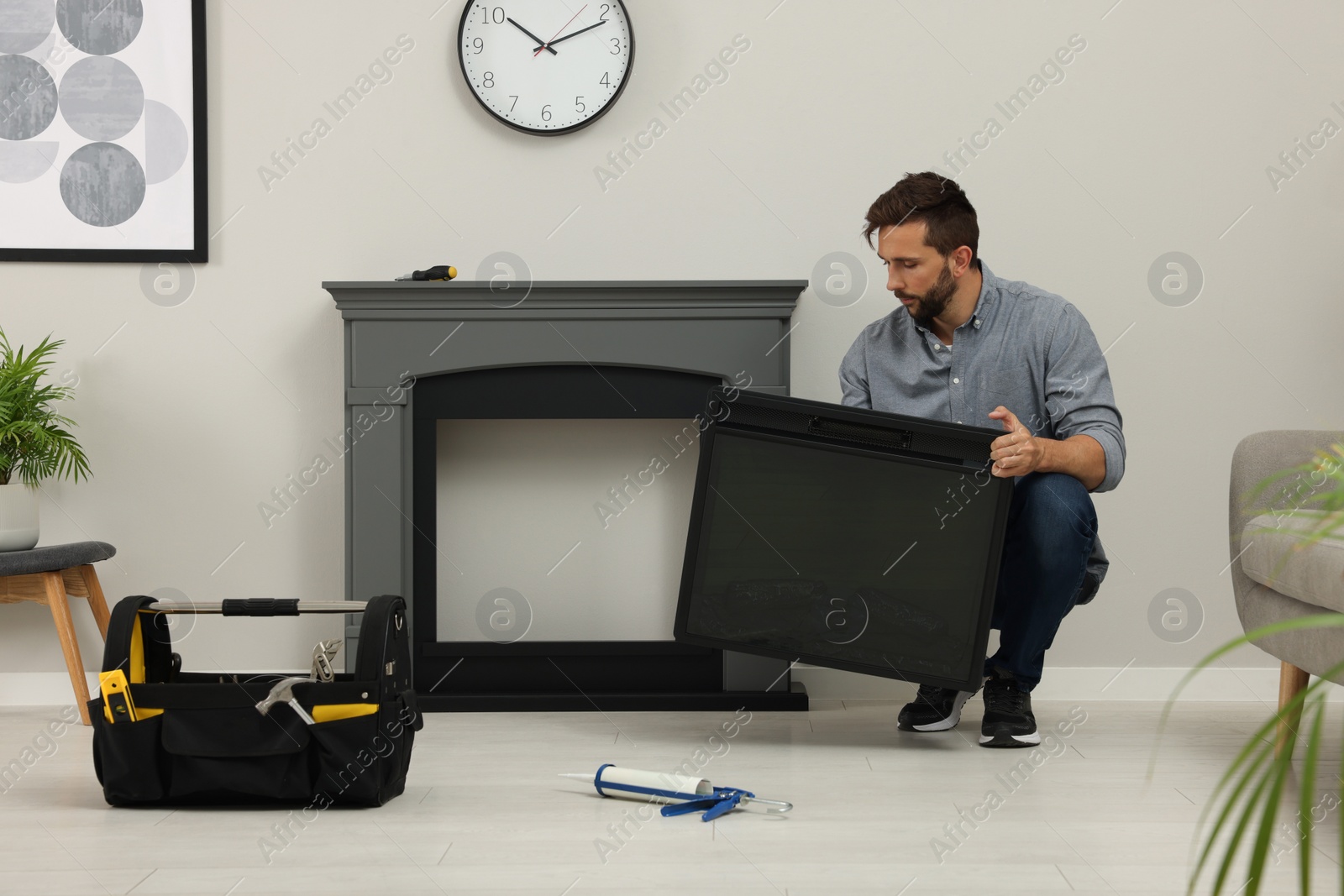 Photo of Man installing electric fireplace near wall in room