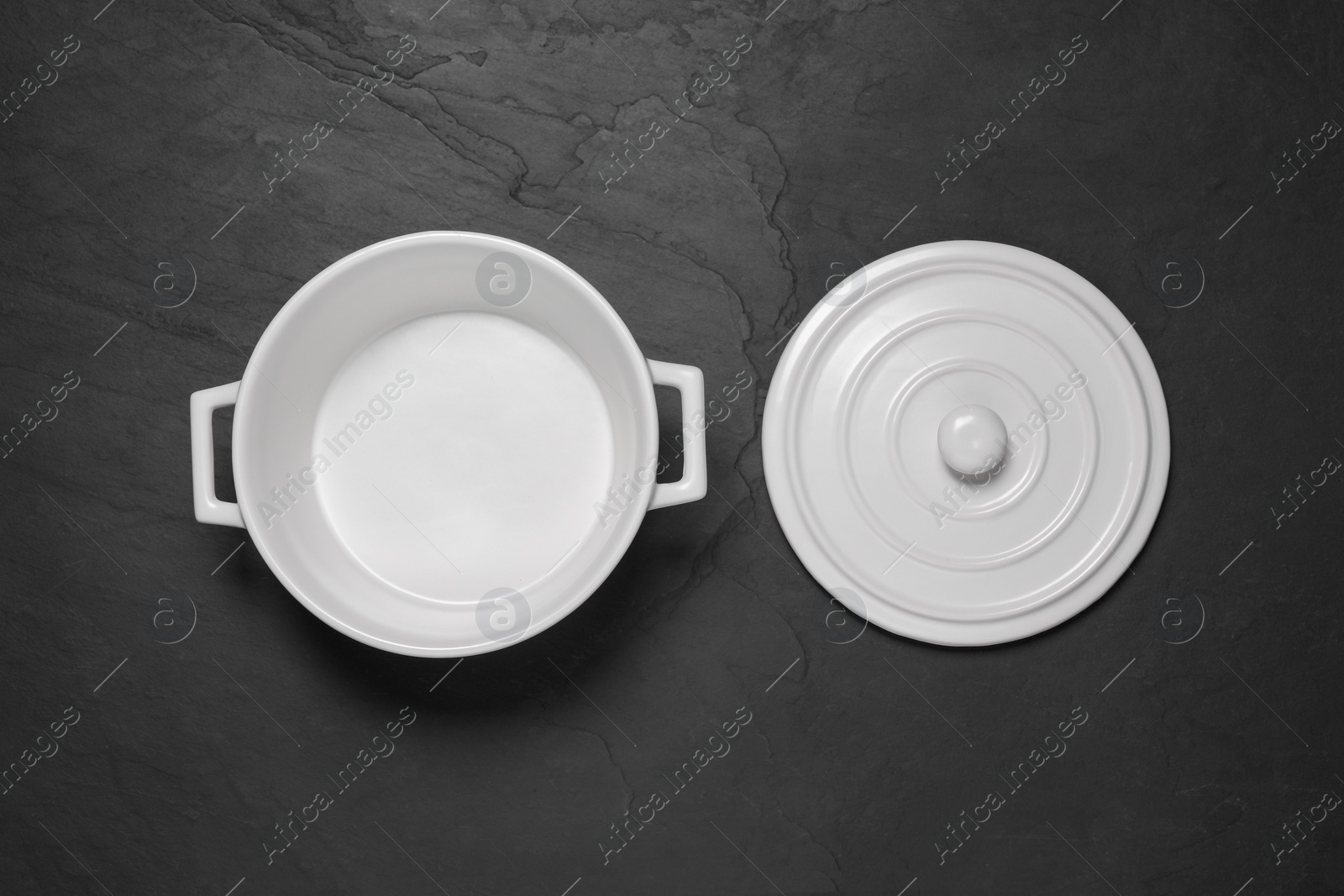 Photo of Empty white pot and lid on black table, flat lay