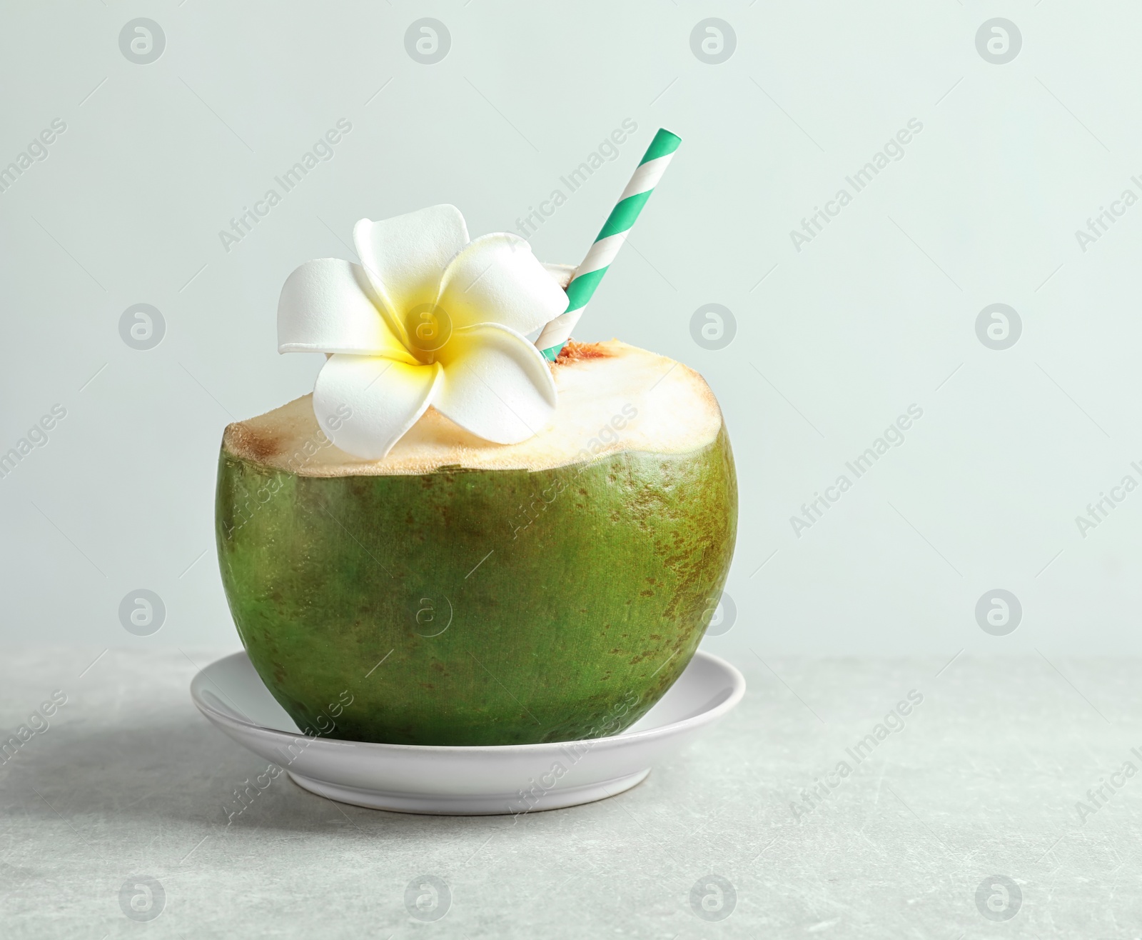 Photo of Fresh green coconut with drinking straw and flower on white background