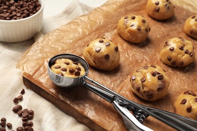 Uncooked chocolate chip cookies and scoop on parchment, closeup