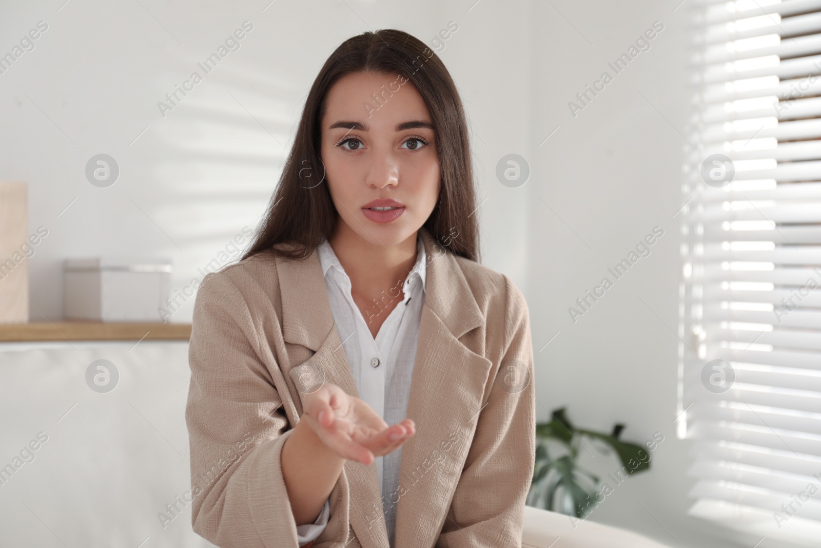 Photo of Young woman talking with her coworkers on video call indoors, view from web camera