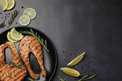 Photo of Plate with tasty salmon steaks on black table, flat lay. Space for text