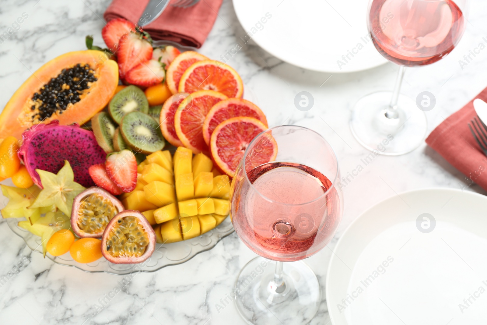 Photo of Delicious exotic fruits and wine on white table