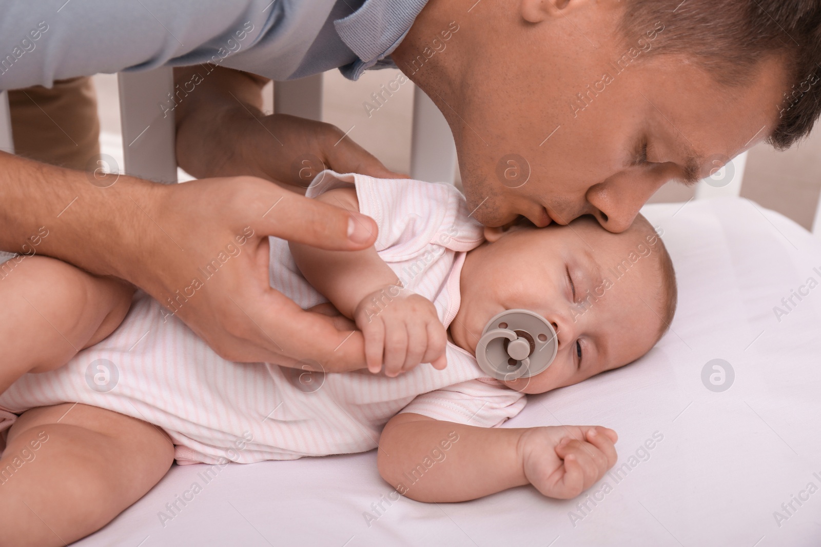 Photo of Happy father kissing his cute sleeping baby