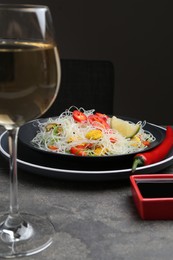 Photo of Stir-fry. Tasty rice noodles with meat and vegetables served on grey textured table