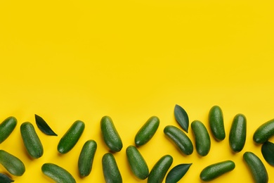 Photo of Fresh whole seedless avocados with green leaves on yellow background, flat lay. Space for text