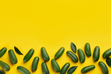 Fresh whole seedless avocados with green leaves on yellow background, flat lay. Space for text