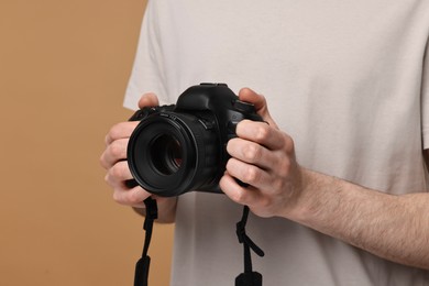 Photo of Photographer holding camera on beige background, closeup