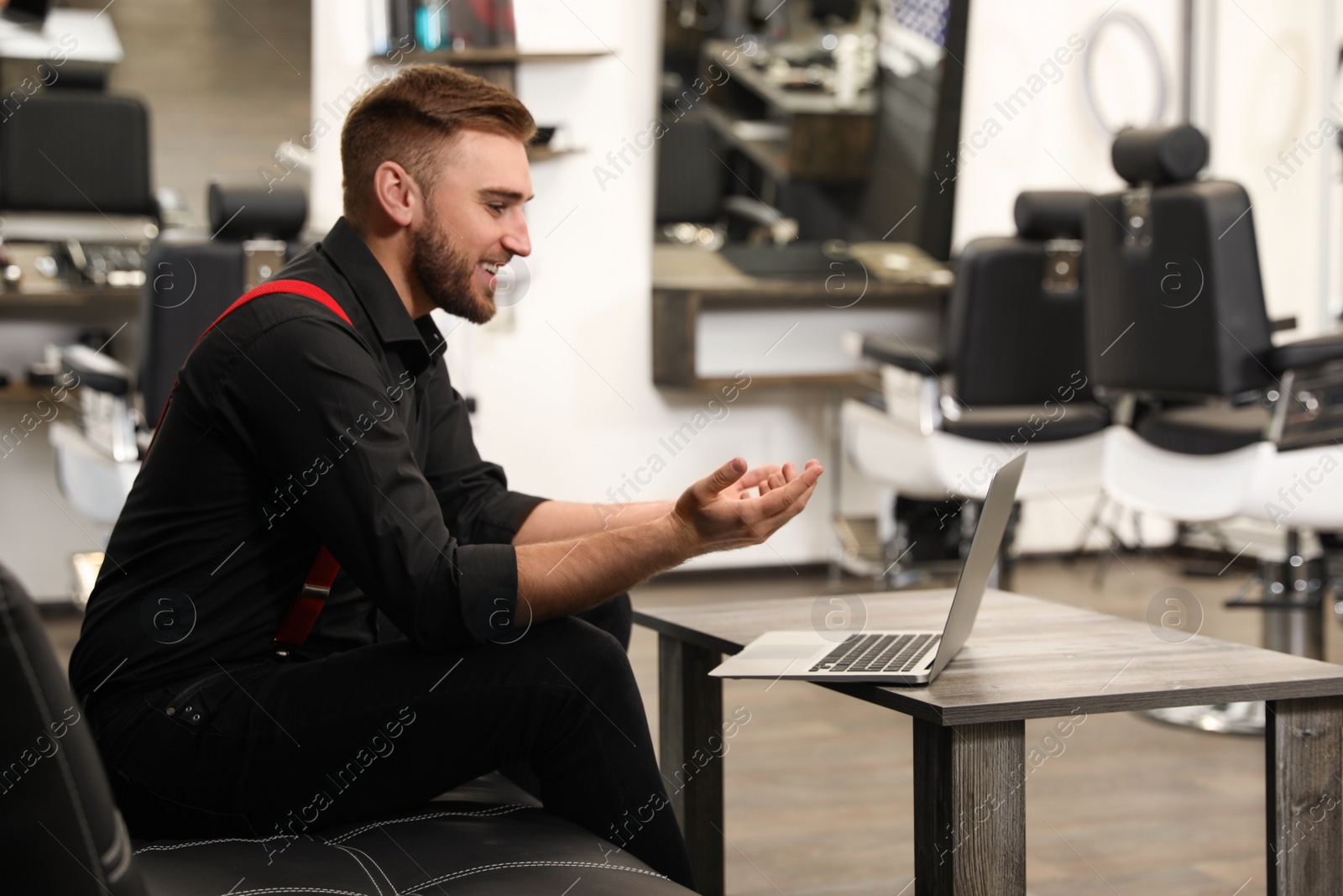 Photo of Young business owner working with laptop in barber shop