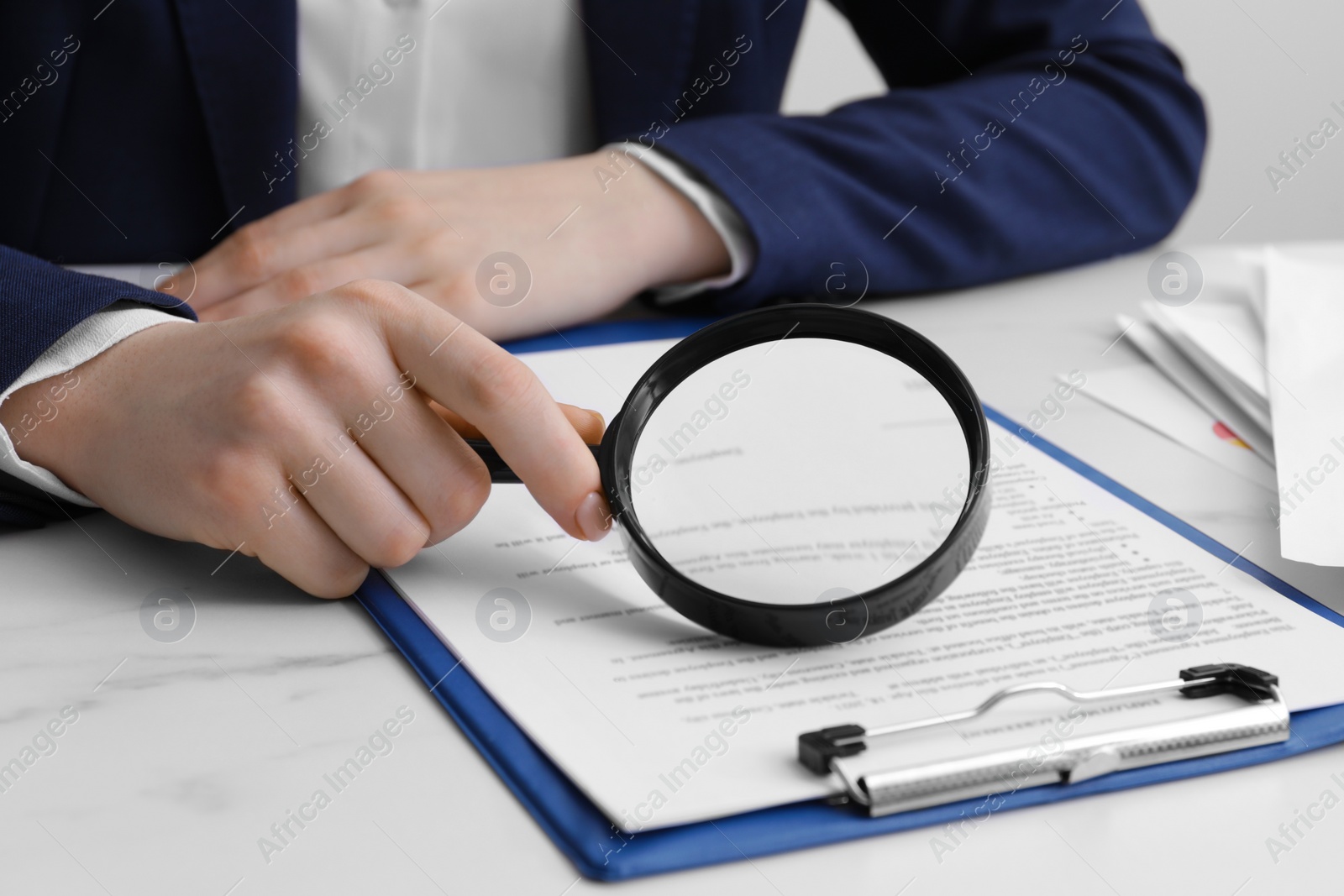 Photo of Woman looking at document through magnifier at white marble table, closeup. Searching concept