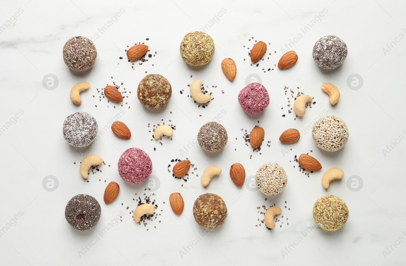 Photo of Delicious vegan candy balls and nuts on white table, flat lay