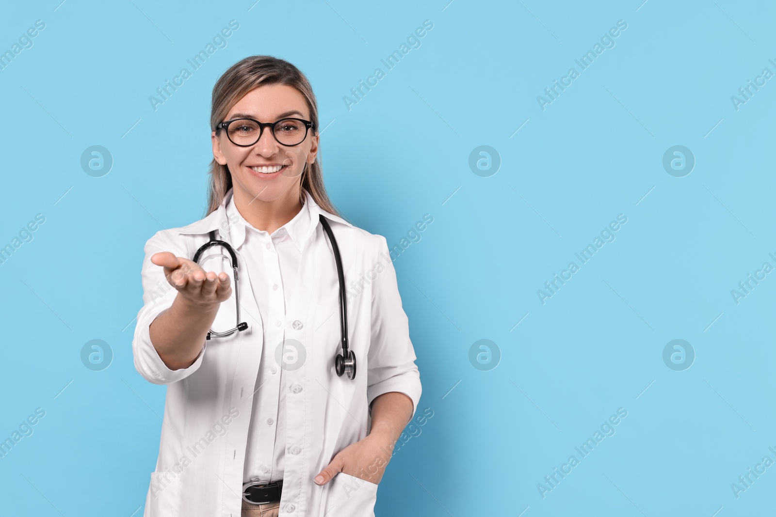 Photo of Portrait of happy doctor with stethoscope on light blue background