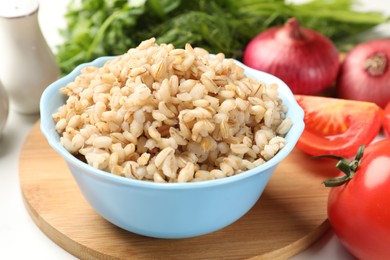 Photo of Delicious pearl barley in bowl on white table, closeup