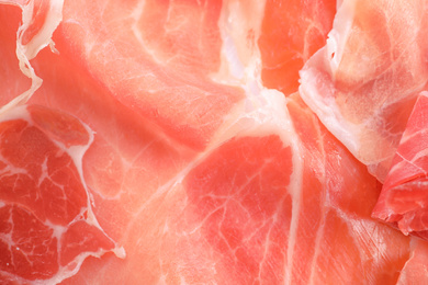 Photo of Tasty prosciutto slices as background, closeup view