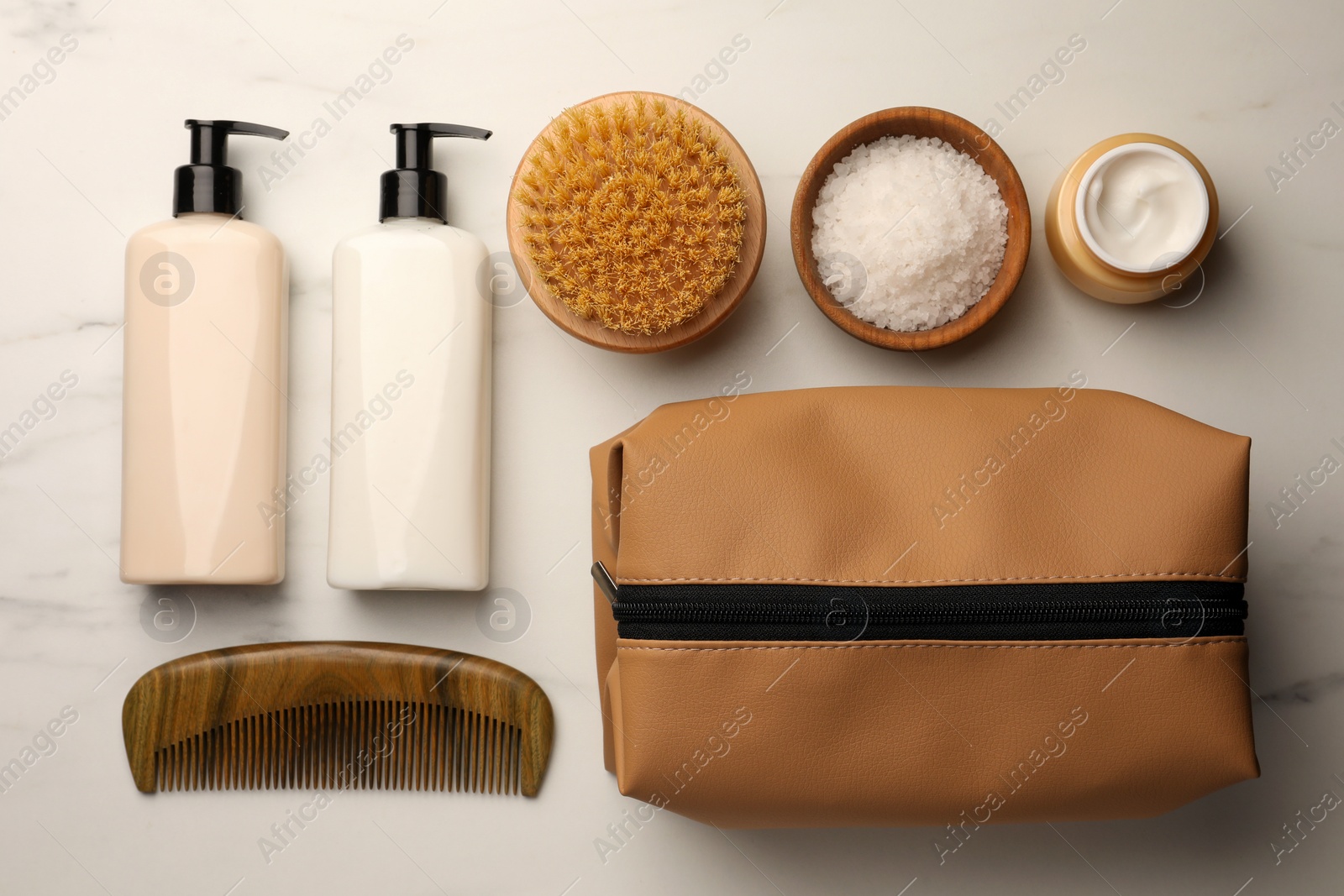 Photo of Preparation for spa. Compact toiletry bag and different cosmetic products on white marble table, flat lay