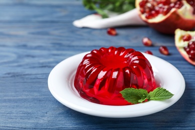 Photo of Delicious fresh red jelly with mint on blue wooden table