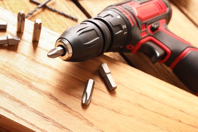 Electric screwdriver with bit set on wooden table, closeup