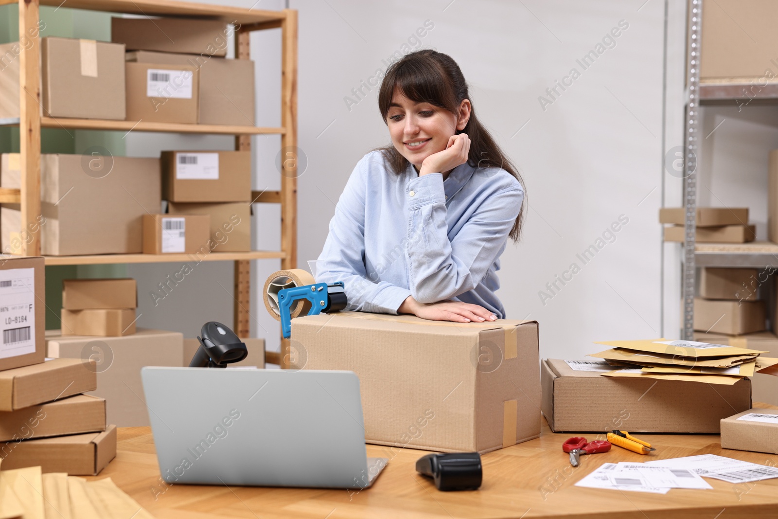 Photo of Parcel packing. Post office worker with box at wooden table indoors