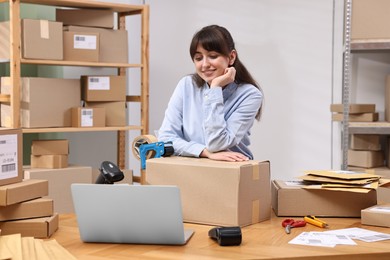 Parcel packing. Post office worker with box at wooden table indoors