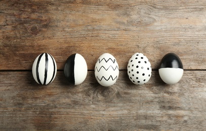 Painted Easter eggs on wooden background, flat lay