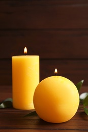 Wax yellow candles of different shapes on wooden table