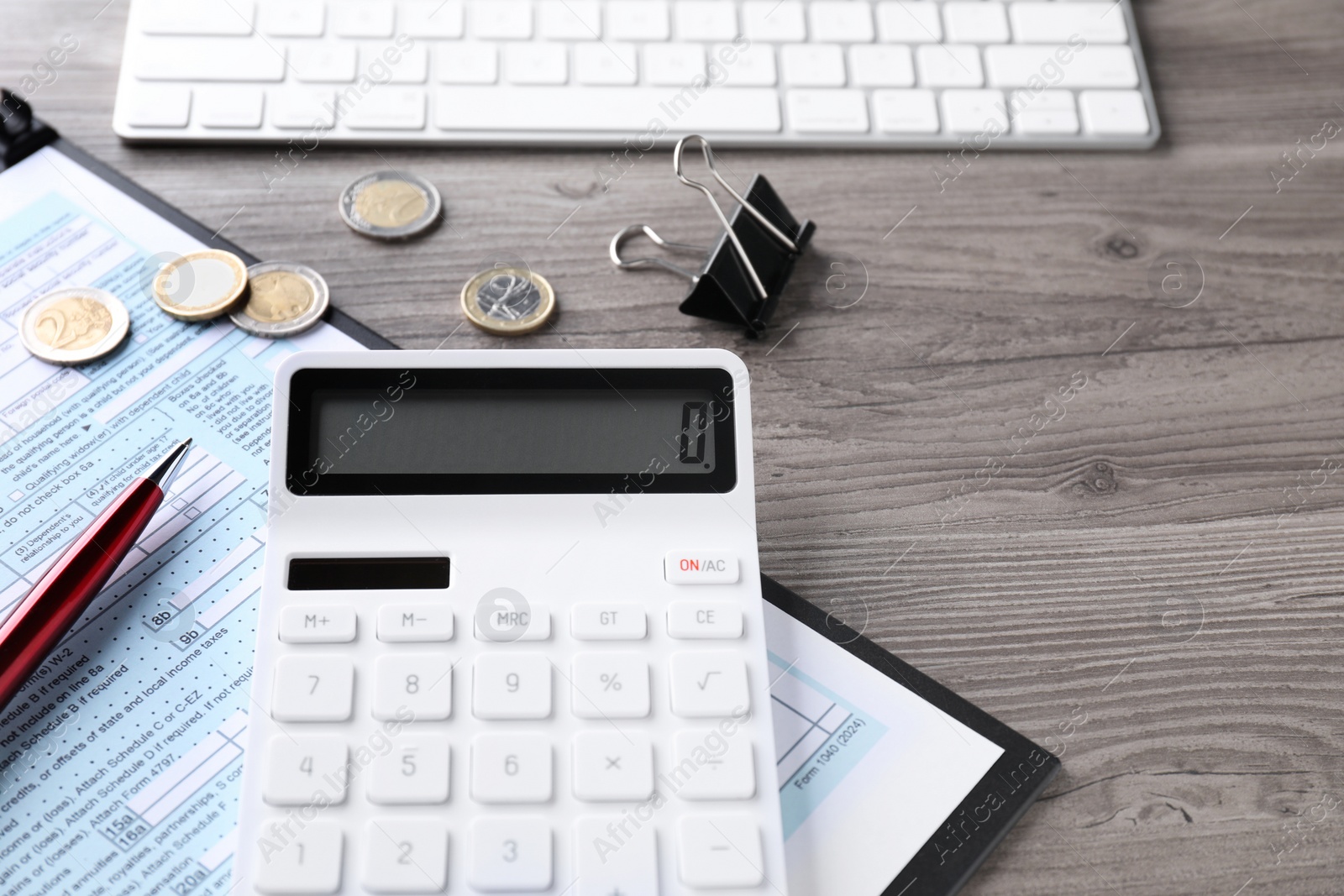 Photo of Tax accounting. Calculator, document, stationery and coins on wooden table, closeup