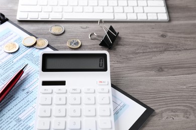 Tax accounting. Calculator, document, stationery and coins on wooden table, closeup