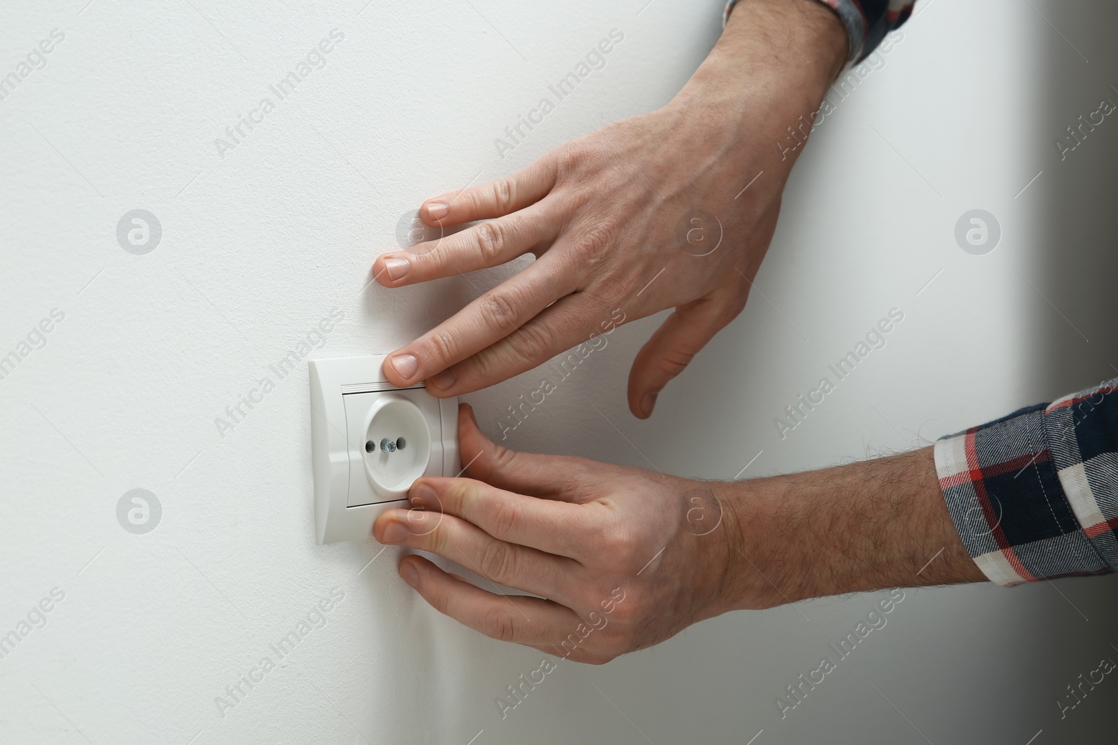 Photo of Professional electrician repairing power socket, closeup view