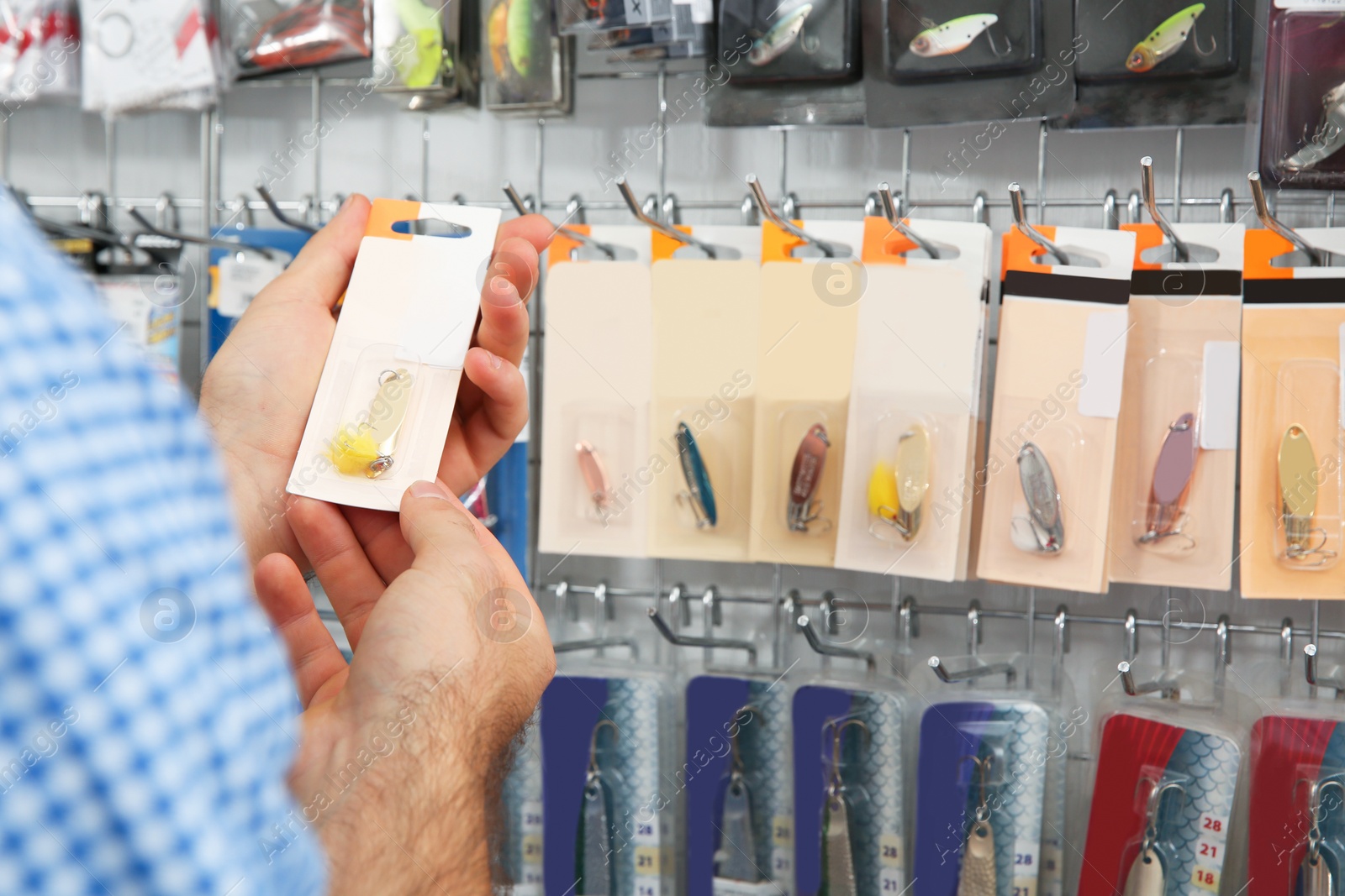 Photo of Customer choosing fishing equipment in sports shop, closeup. Space for text