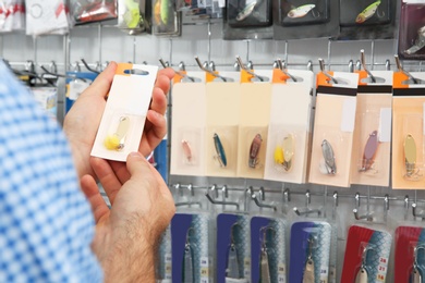 Photo of Customer choosing fishing equipment in sports shop, closeup. Space for text