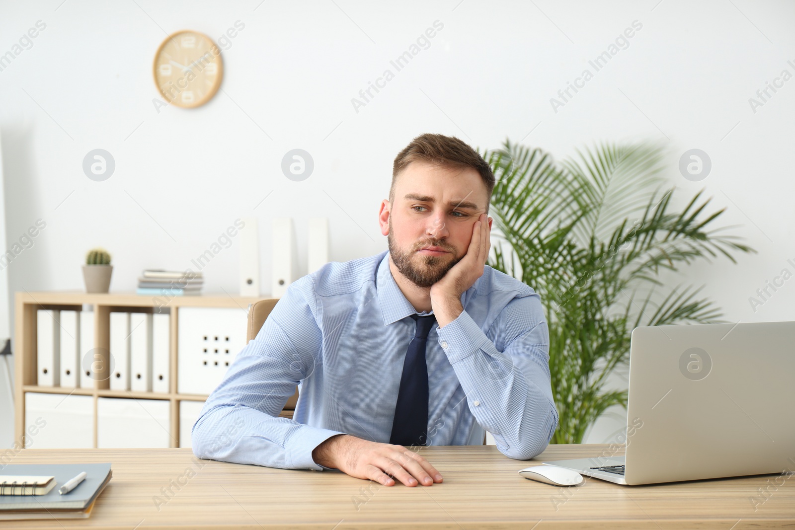 Photo of Lazy young office employee procrastinating at workplace