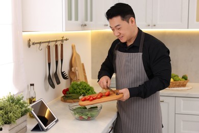 Photo of Man making fresh salad in kitchen. Cooking process