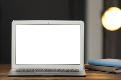 Photo of Laptop with blank screen on table indoors. Space for text
