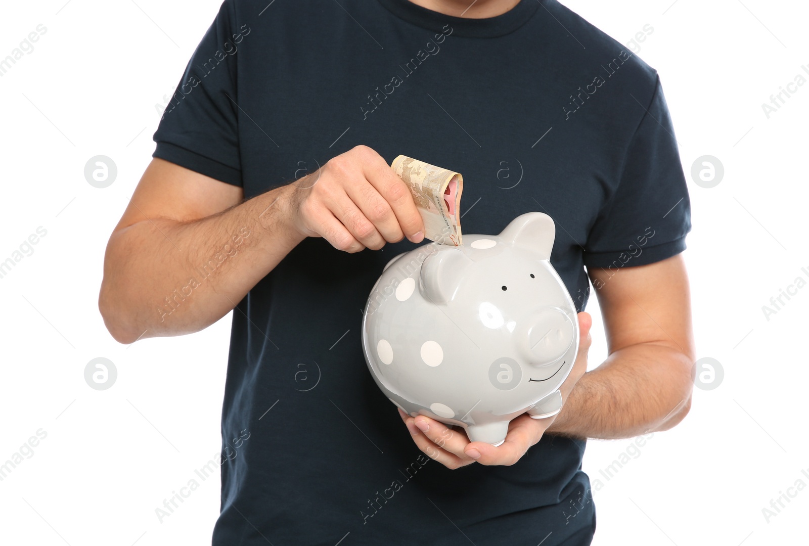 Photo of Young man putting money into piggy bank on white background, closeup