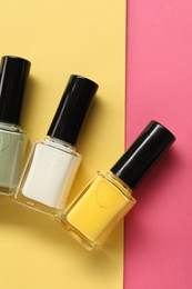 Beautiful nail polishes in bottles on color background, flat lay