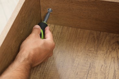 Man with screwdriver assembling drawer, closeup view