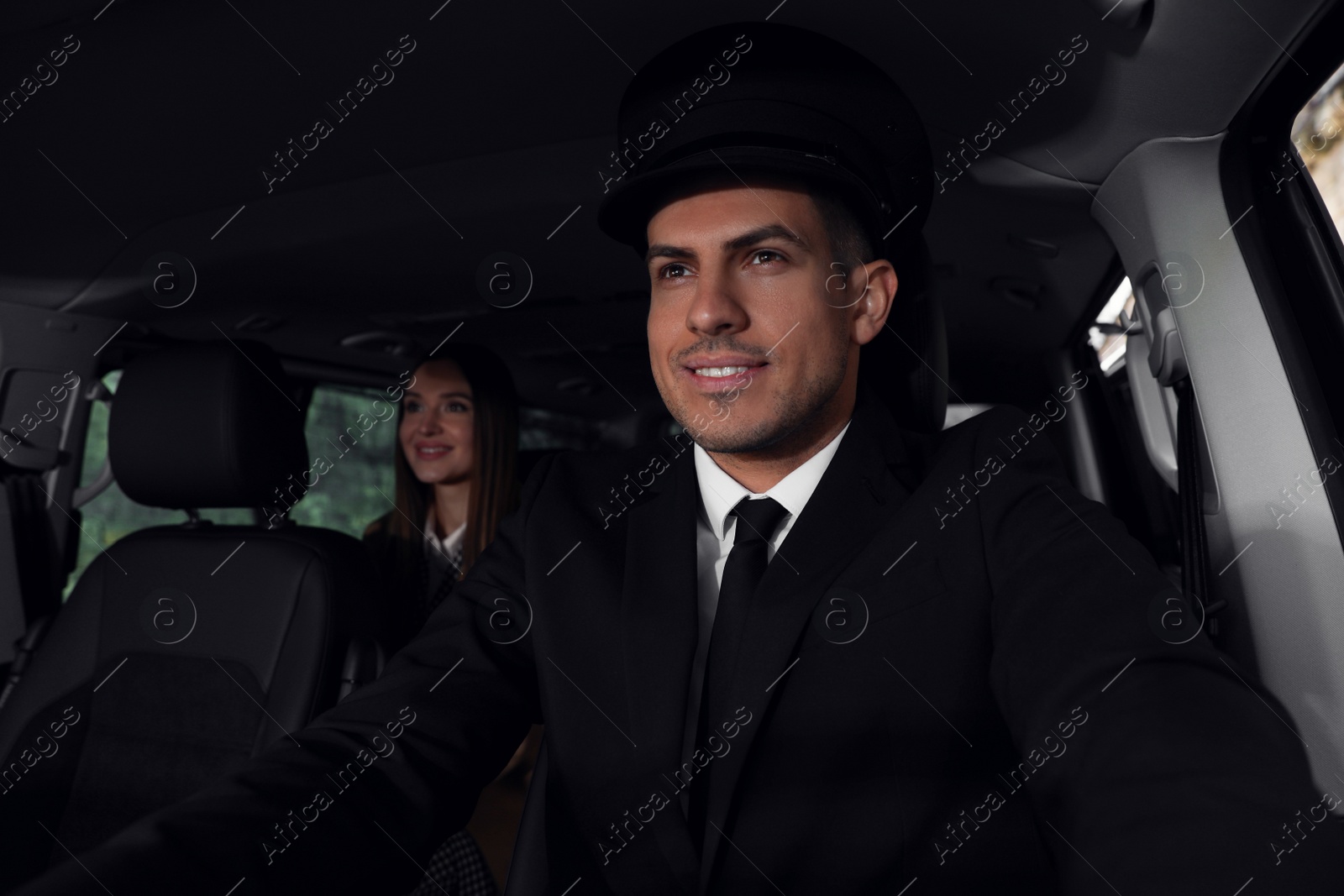 Photo of Professional driver and businesswoman in luxury car. Chauffeur service