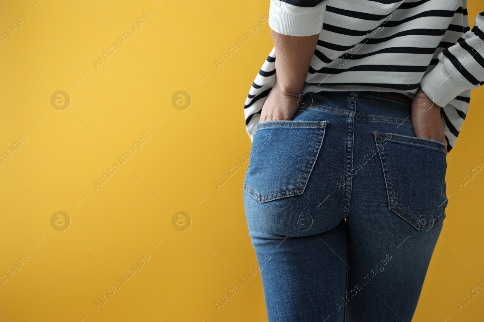 Photo of Woman wearing jeans on yellow background, closeup. Space for text