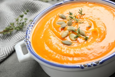 Photo of Delicious pumpkin soup in bowl on grey table, closeup