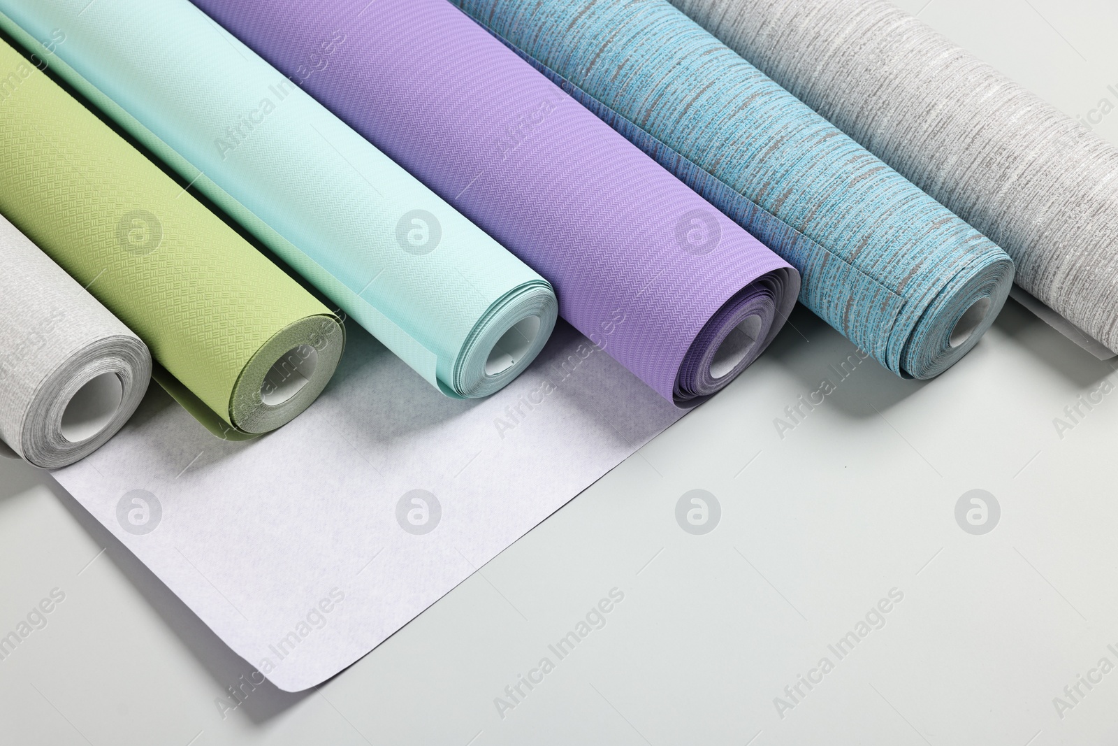 Photo of Different stylish wallpaper rolls on light background