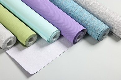 Different stylish wallpaper rolls on light background