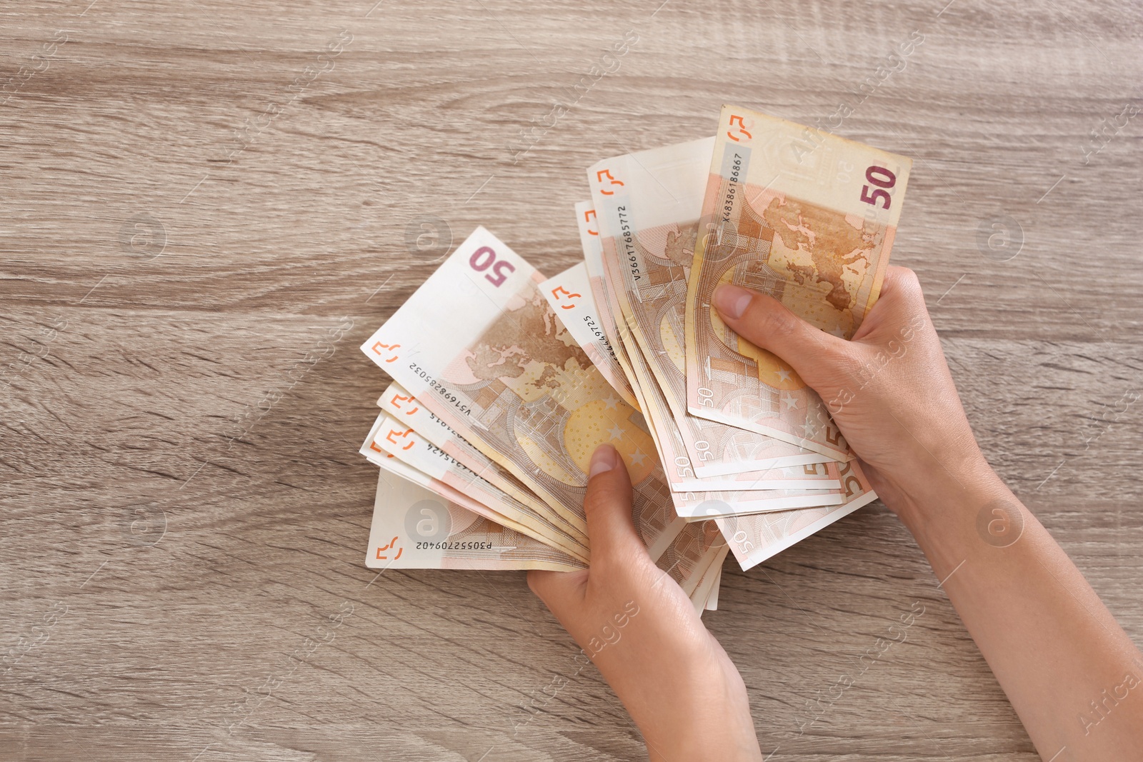 Photo of Woman with Euro banknotes at wooden table, top view