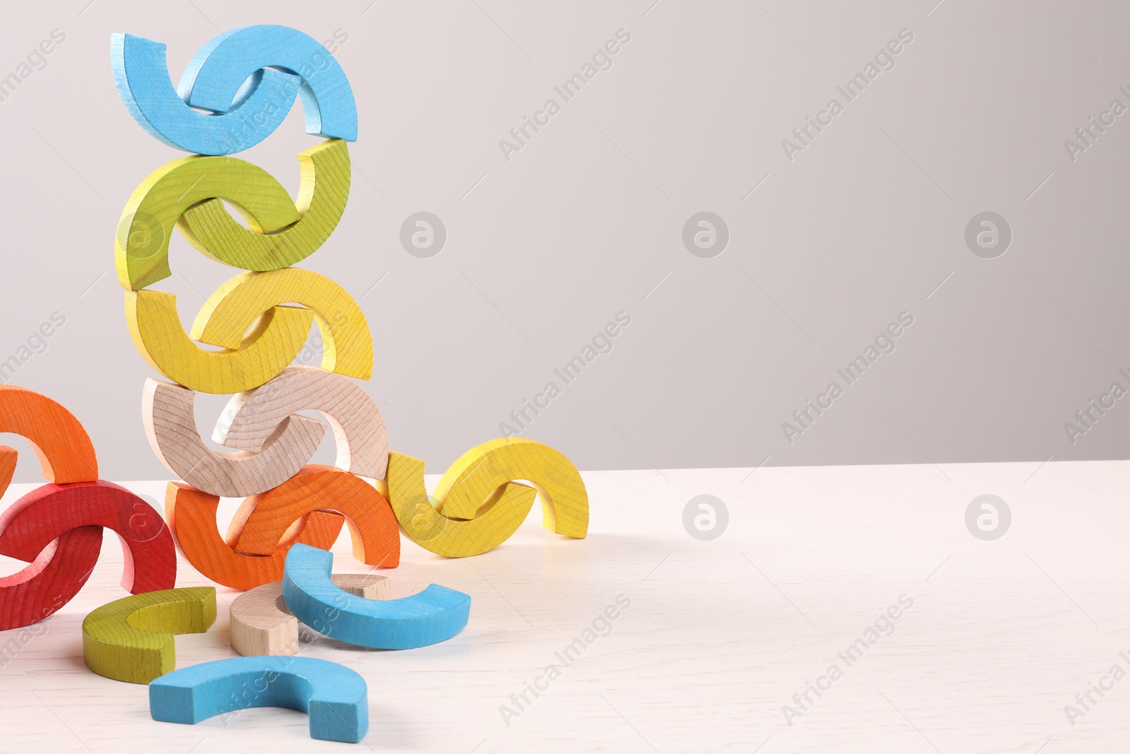 Photo of Colorful wooden pieces of playing set on white table against light grey background, space for text. Motor skills development