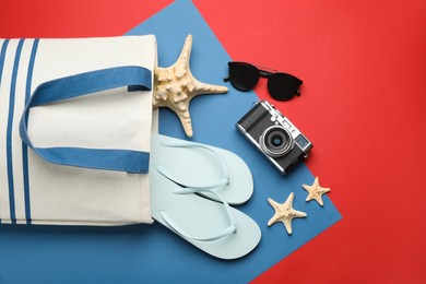 Photo of Stylish bag with beach accessories on color background, flat lay