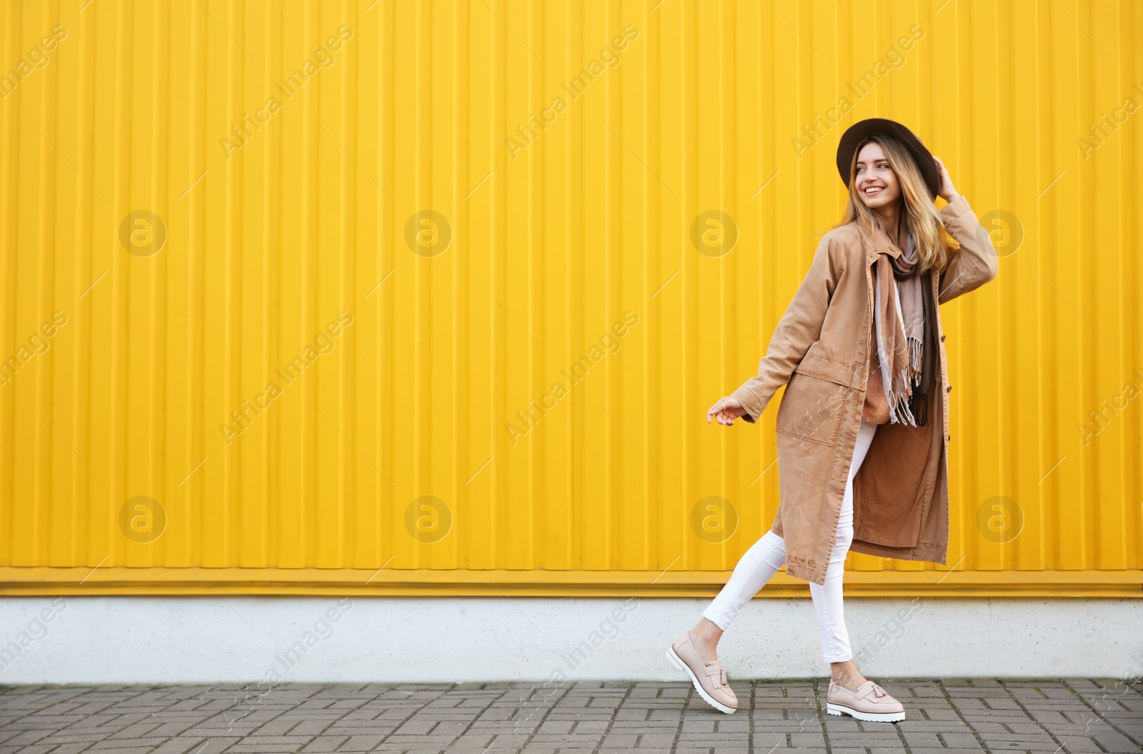 Photo of Beautiful young woman in stylish autumn clothes near yellow fence. Space for text