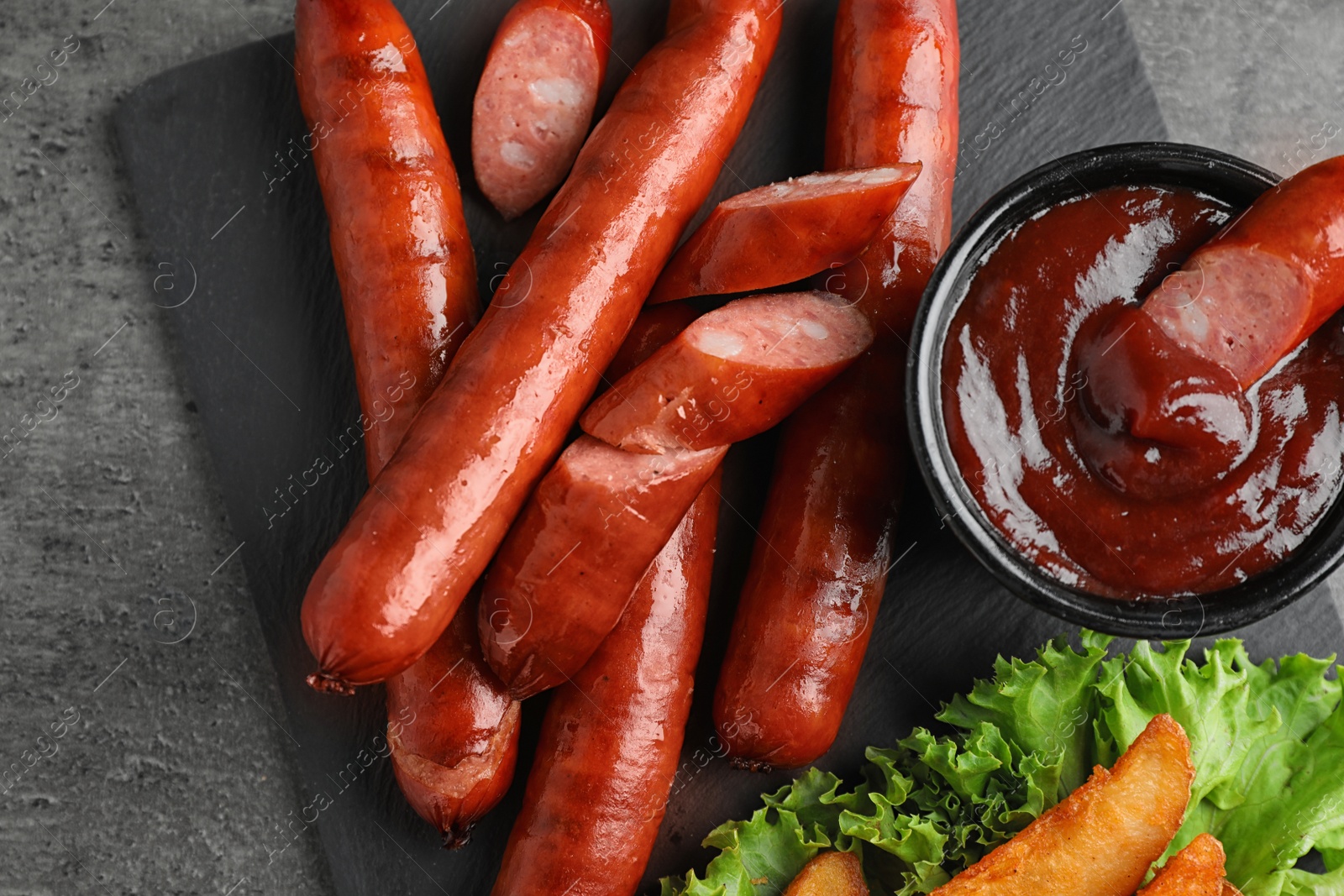 Photo of Delicious grilled sausages and vegetables on grey table, top view