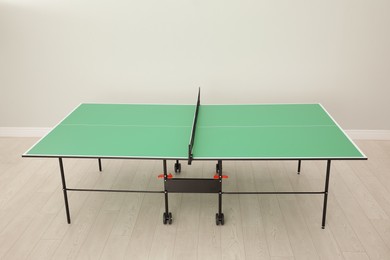 Photo of One green ping pong table with net indoors