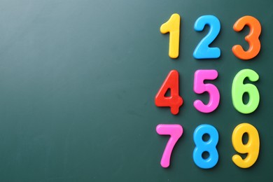 Colorful numbers on green background, flat lay. Space for text