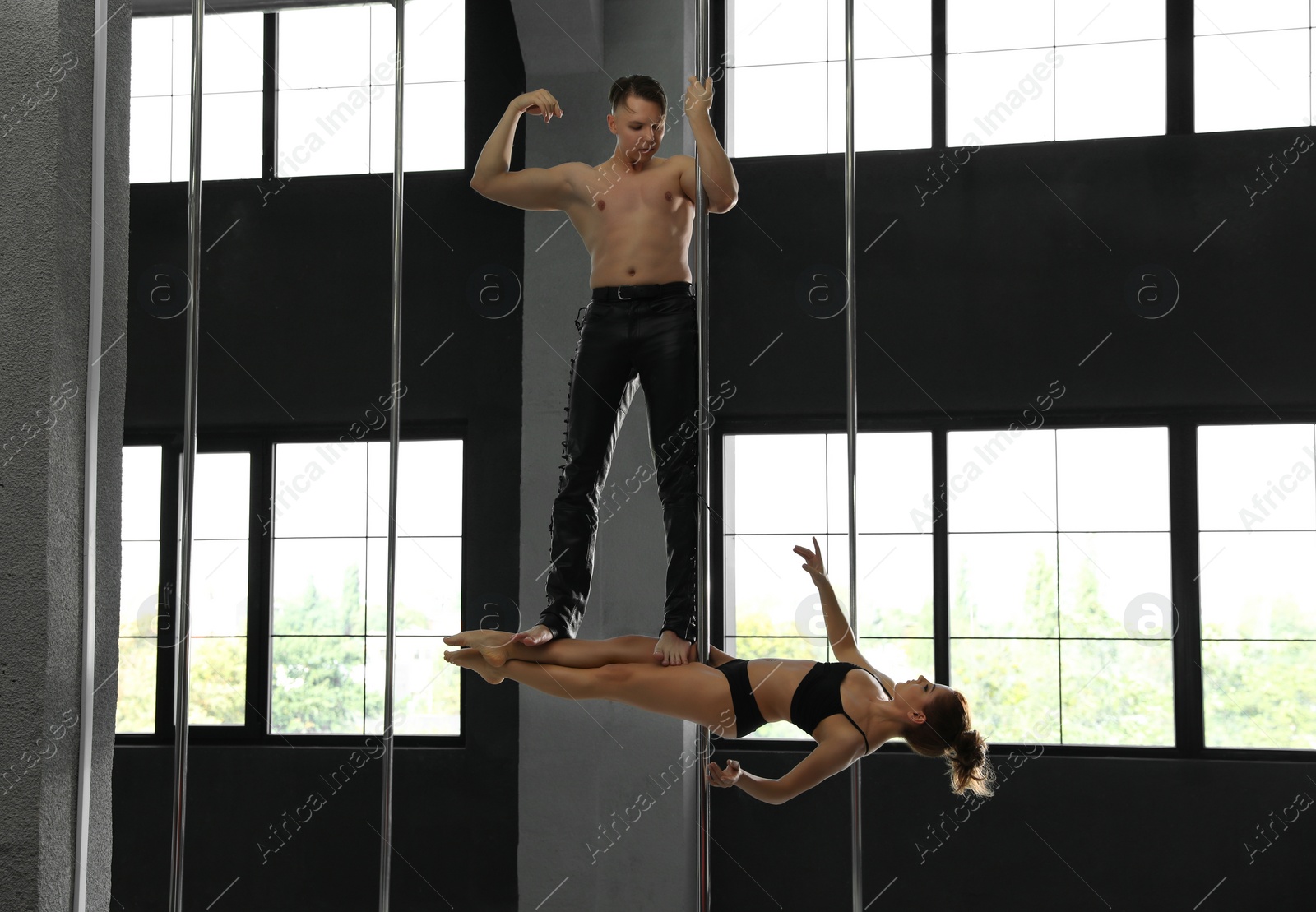 Photo of Young couple dancing in studio with poles